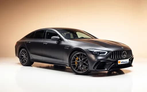 Mercedes-AMG GT 63 S noir mat, vue de trois quarts avant en studio sur fond beige, plaque avant siglée WheelTrust